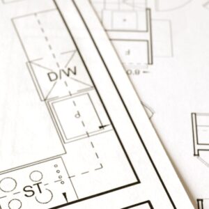 Equipo Close-up view of an architectural floor plan on paper showcasing detailed room layouts and measurements.